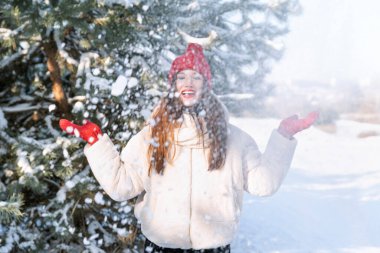 Mutlu genç kadın kışın parkta eğleniyor. Esmer kız kar atıyor ve gülüyor.
