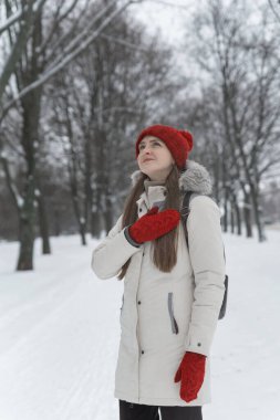 Kış ormanındaki karlı ağaçların arasında duran güzel genç bir kadın. Dikey çerçeve
