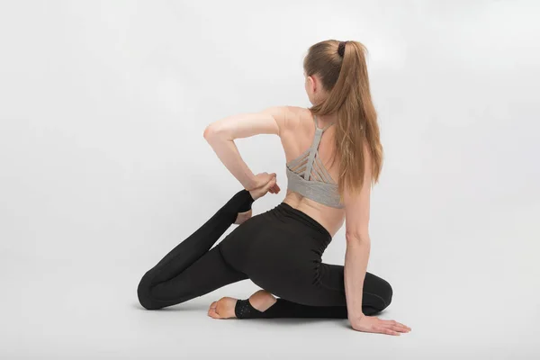 年轻纤细的女人在白色背景上做柔韧的运动 女孩在练体操或瑜伽 — 图库照片