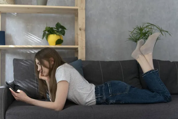 Mit Dem Handy Der Hand Liegt Sie Auf Dem Sofa — Stockfoto