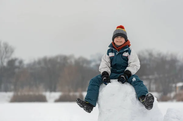 Усміхнений Хлопчик Семи Років Сидить Сніговій Вежі Дитина Будує Сніговий — стокове фото