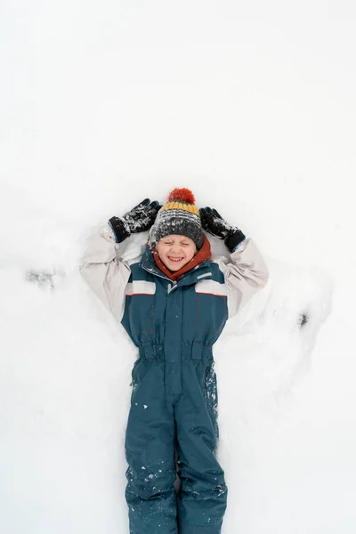 Веселий Хлопчик Лежить Снігу Робить Сніговий Ангел Щасливе Дитинство Вид — стокове фото