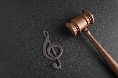 Siyah arka planda tokmağın yanında üçlü anahtar. Müzik telif hakları. Müzik korsanlığı konsepti