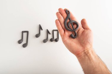 Erkek eli müzikal notayı tutar, anahtar ve arka plan notaları. Müzik eğitimi kavramı