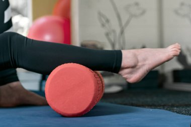 Baldır kaslarını çalıştırmak için paten. Ayak masajı için masaj aleti kullanan bir kadın. Bağ gevşemesi için masaj silindiri