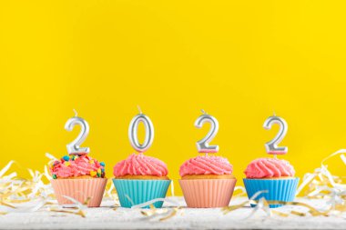 Sarı zemin üzerinde 2022 numara mumlar olan parlak Noel teması. Boşluğu kopyala