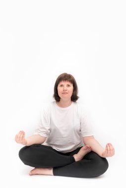 Beyaz arka planda yoga yapan beyaz tenli bir kadının portresi. Ardha-padmasana, yarım lotus pozu. Dikey çerçeveci. Boşluğu kopyala.