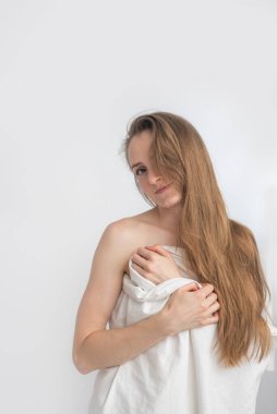 Uzun saçlı çıplak kadın beyaz çarşafla kaplıdır. Sabah güzel bir kızın portresi