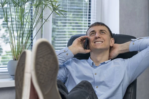 Uśmiechnięty Leniwy Mężczyzna Siedzi Biurku Rozmawia Przez Telefon Szczęśliwy Młody — Zdjęcie stockowe