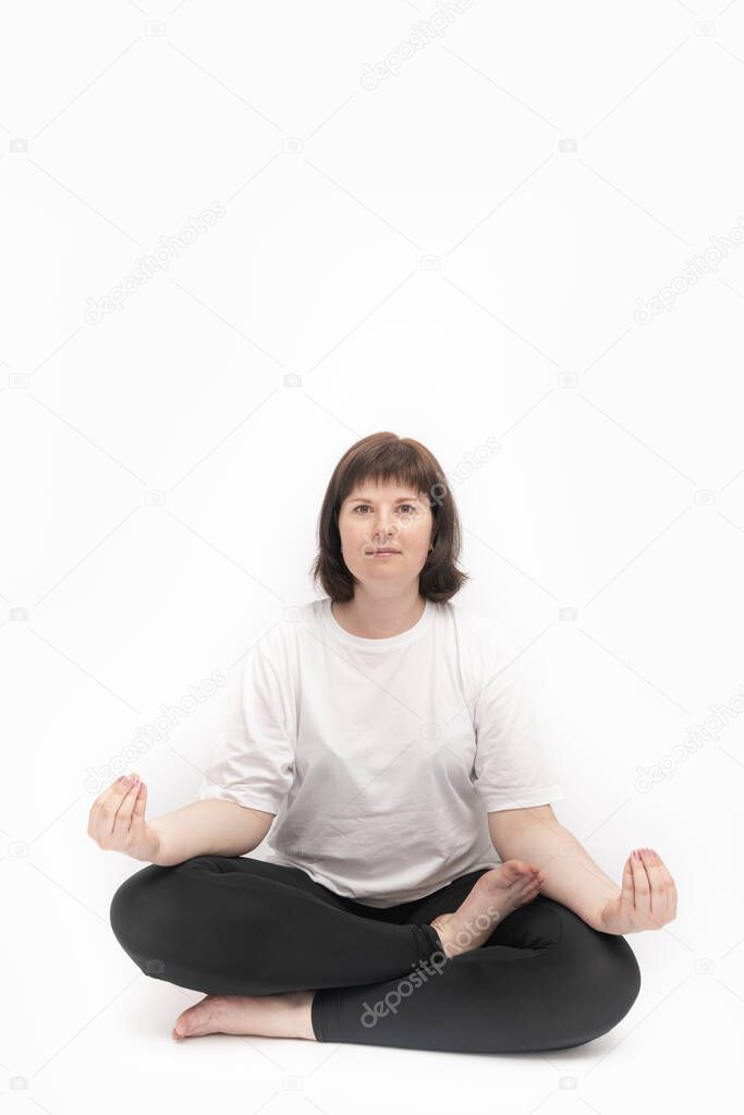 Portrait of caucasian plus size woman on white background practicing yoga. Ardha-padmasana, half lotus pose. Vertical framer. Copy space.