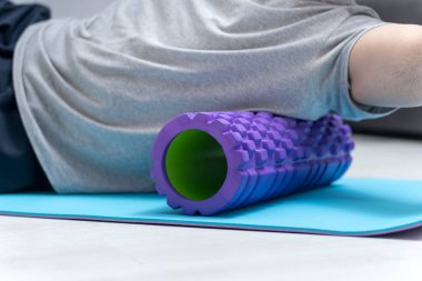 Man doing fascia exercise. Foam roller back pain treatment and myofascial release. Tools for self-massage. Workout at home