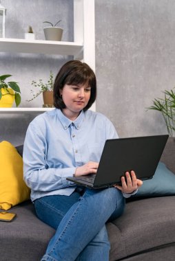 Plus size woman working at laptop at home. Business woman, freelancer. Vertical frame.