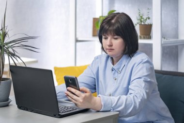Young woman is working at her workplace. Business woman with laptop and phone. Remote work.
