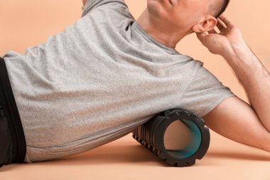 Man doing fascial exercise on side surface of back. Handsome man performs myofascial release massage of trigger points. Side view.