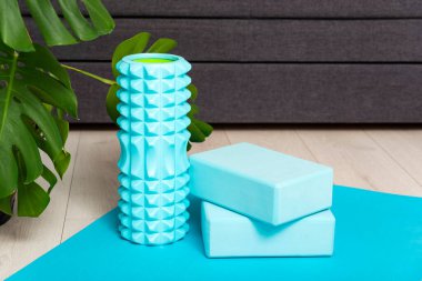 Yoga bricks and myofascial roller on yoga mat at home. Sport equipment. Stretching and self-massage instruments