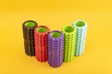 Colored roller for myofascial relaxation on yellow background. Foam Rollers. Fitness Equipment for myofascial release
