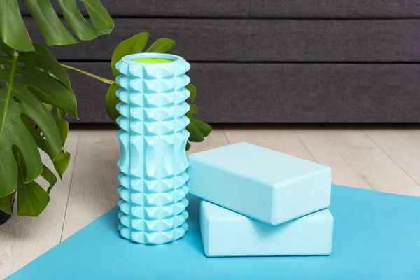Yoga bricks and myofascial roller on yoga mat at home. Sport equipment. Stretching and self-massage instruments