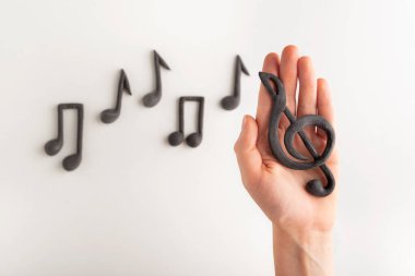 Violin key on the palm of your hand on notes background. Treble clef and notes on white background. Music symbol