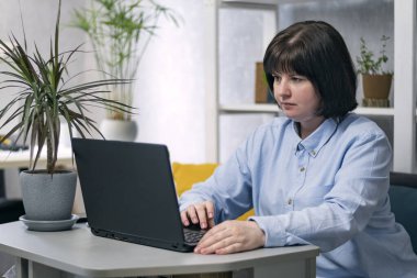 Young woman is working at her workplace. Business woman with laptop in home office.
