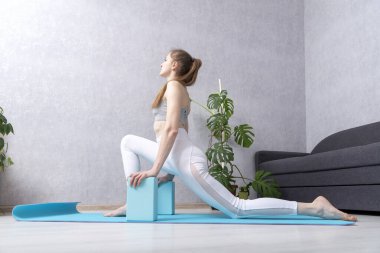 Girl does stretch using yoga foam blocks. Practice yoga at home. Morning gymnastics. Self-training.