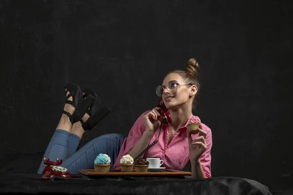 Mädchen Liegt Mit Retro Handy Und Cupcake Der Hand Auf — Stockfoto