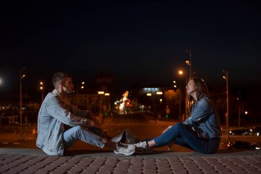 Adam ve kız şehrin arka planında karşılıklı oturuyorlar. Boşluğu kopyala.