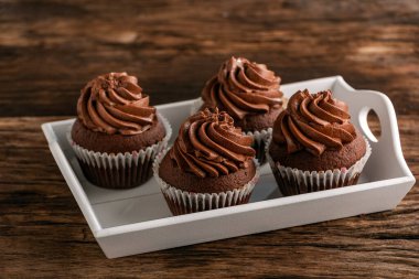 Çikolatalı kekler. Tahta masadaki tepside çikolata kremalı. Ev yapımı kekler.