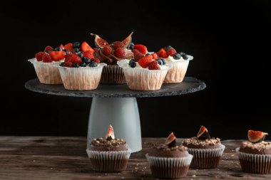 Siyah arka planda yaz meyveli kekler. Çikolata ve vanilyalı kek karışımı.