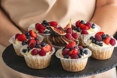 Böğürtlen karışımıyla süslenmiş taze ağız. Tabakta ev yapımı vanilyalı kek. Kapat.
