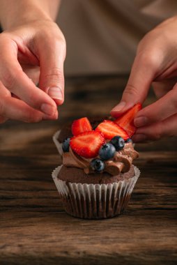Şekerci elleri keki taze dutlarla süsler. Çilekli ve yaban mersinli kek. Keki kapat.