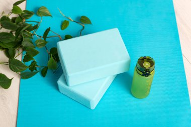 Mavi yoga minderi, su şişesi ve yoga tuğlaları. Gerdirme aletleri. Evde egzersiz yap..