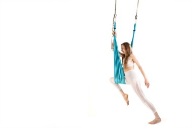 Kız hamakta beyaz arka planda çalışıyor. Hava jimnastiği ya da sinek yogası egzersizi. Egzersiz ve spor hamağı ile esneme