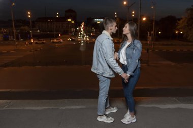 Genç ve güzel bir çift şehrin arka planında durup konuşur. Romantik randevu