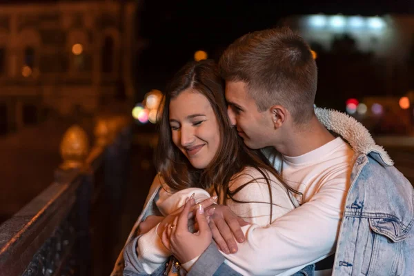 幸せな笑顔の若いカップルは 夜の街の背景に抱擁 屋外関係 — ストック写真