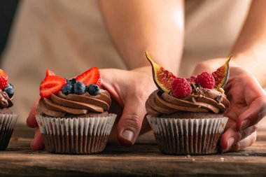 Kadınların elleri taze böğürtlenlerle süslenmiş çikolatalı kekleri tutar. Pasta şefi kek tutuyor.