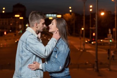 Genç ve güzel bir çift, şehrin arka planında sarılıyorlar.