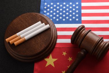 ABD ve Çin bayrağının arka planında sigara ve yargıç tokmağı var. Yasadışı tütün ürünleri taşımacılığı. Kaçakçılık