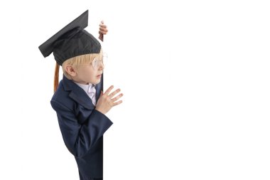 Beyaz tahtanın arkasından bakan tatlı, şaşkın öğrenci. Okul üniformalı, büyük gözlüklü ve öğrenci şapkalı bir çocuk. Boşluğu kopyala