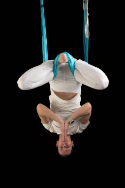 Kadın sinek yoga eğitmeni lotus pozisyonunda baş aşağı asılı duruyor. Hava anti-yerçekimi yogası