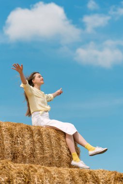 Hasat sırasında çiftlikteki yüksek samanlıkta dinlenen mutlu genç kadın. Kırsal tatil