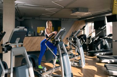 Sexy female with slim body running in empty gym. Lady doing workout in modern gym. Fit girl in aerobics class