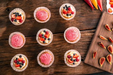 Düz vanilyalı çörekler, taze böğürtlenler ve incirlerle koyu ahşap masa üzerinde yatıyordu. Üst Manzara. Tatlı hamur işleri. Şekerlemeci