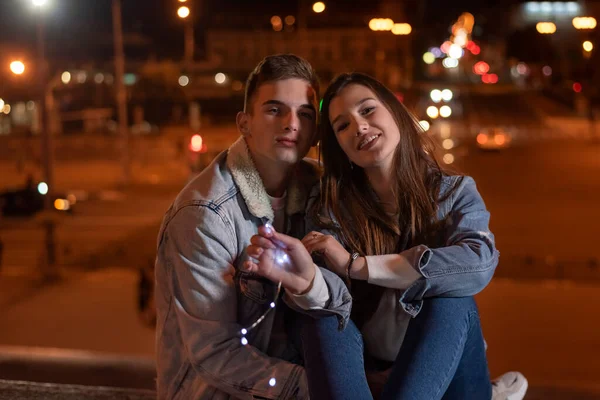 Young Couple Sitting Pavement Evening City Background Garland Hands Night — Stok fotoğraf