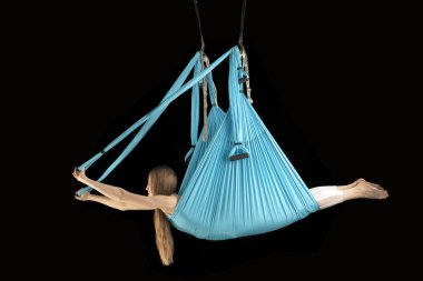 Side view portrait of girl doing tricks in the air on fabric hammocks in the gym. Fly yoga. Aerial gymnastics