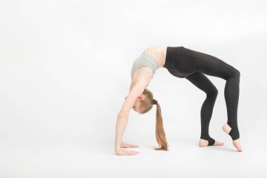 Urdhva Dhanurasana. Pruva Tekerleği Pozu. Kız, beyaz arka plan eğitimi sırasında jimnastikçi. Yoga koçu Asana 'yı canlandırıyor. Güzel bir genç kadın esnekliği eğitir..