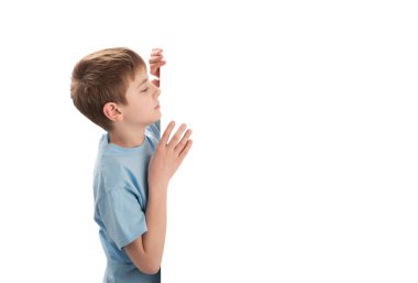 Young Caucasian schoolboy peeking out from blank copy space. Boy with an empty poster. Copy space