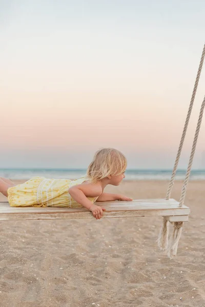Fair Haired Girl Play Wooden Swing Summer Evening Sea Background — Stok fotoğraf