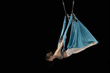 Sporcu kadının tam boy görüntüsü baş aşağı asılı dururken aero uçuş yoga pozisyonu uyguluyor. Aero anti yerçekimi yogası
