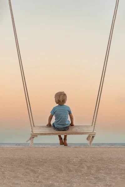 Fair Haired Boy Sits Swing Sea Shore Sunset Magic Surreal — Stok fotoğraf