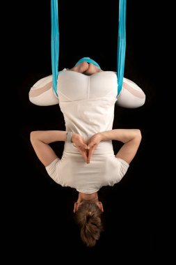 Yoga öğretmeni sinek yogası sırasında ters dönmüş asanaları gösteriyor. Kız ters yerçekimi yogası yapıyor.